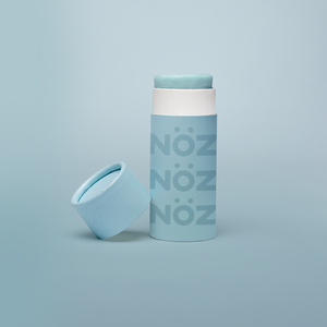 blue background, with blue branded NÖZ sunscreen stick, lid sitting next to stick