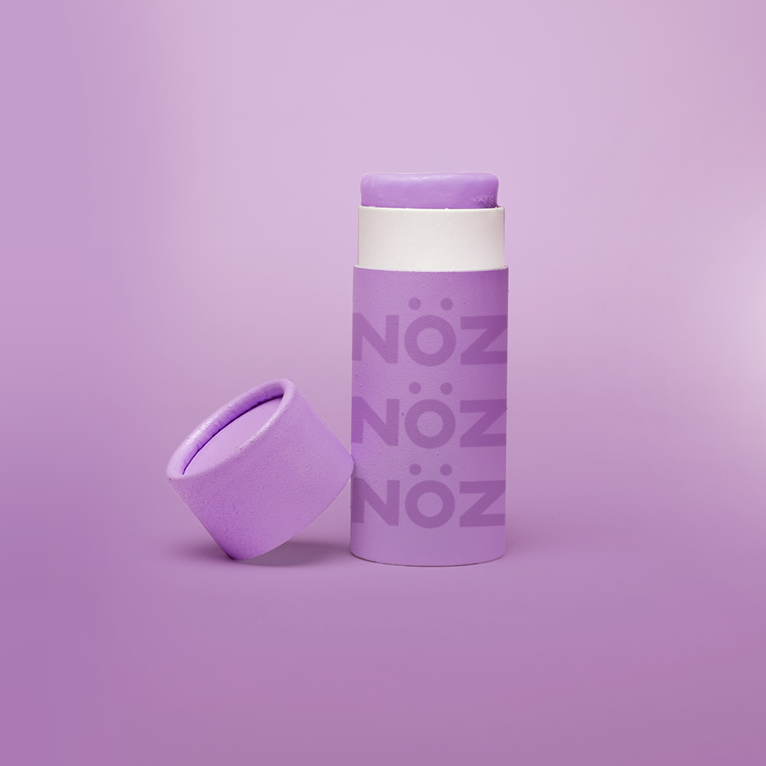 purple background, with purple branded NÖZ sunscreen stick, lid sitting next to stick